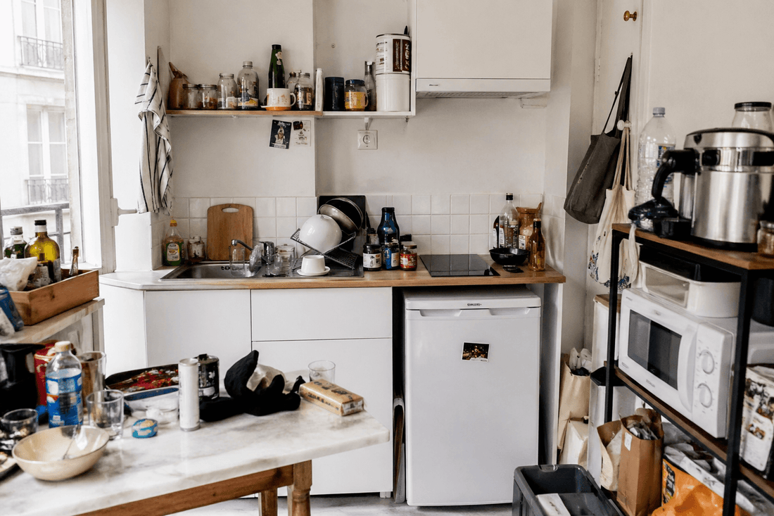 petite cuisine en désordre dans un studio parisien avec plan de travail encombré et rangement limité